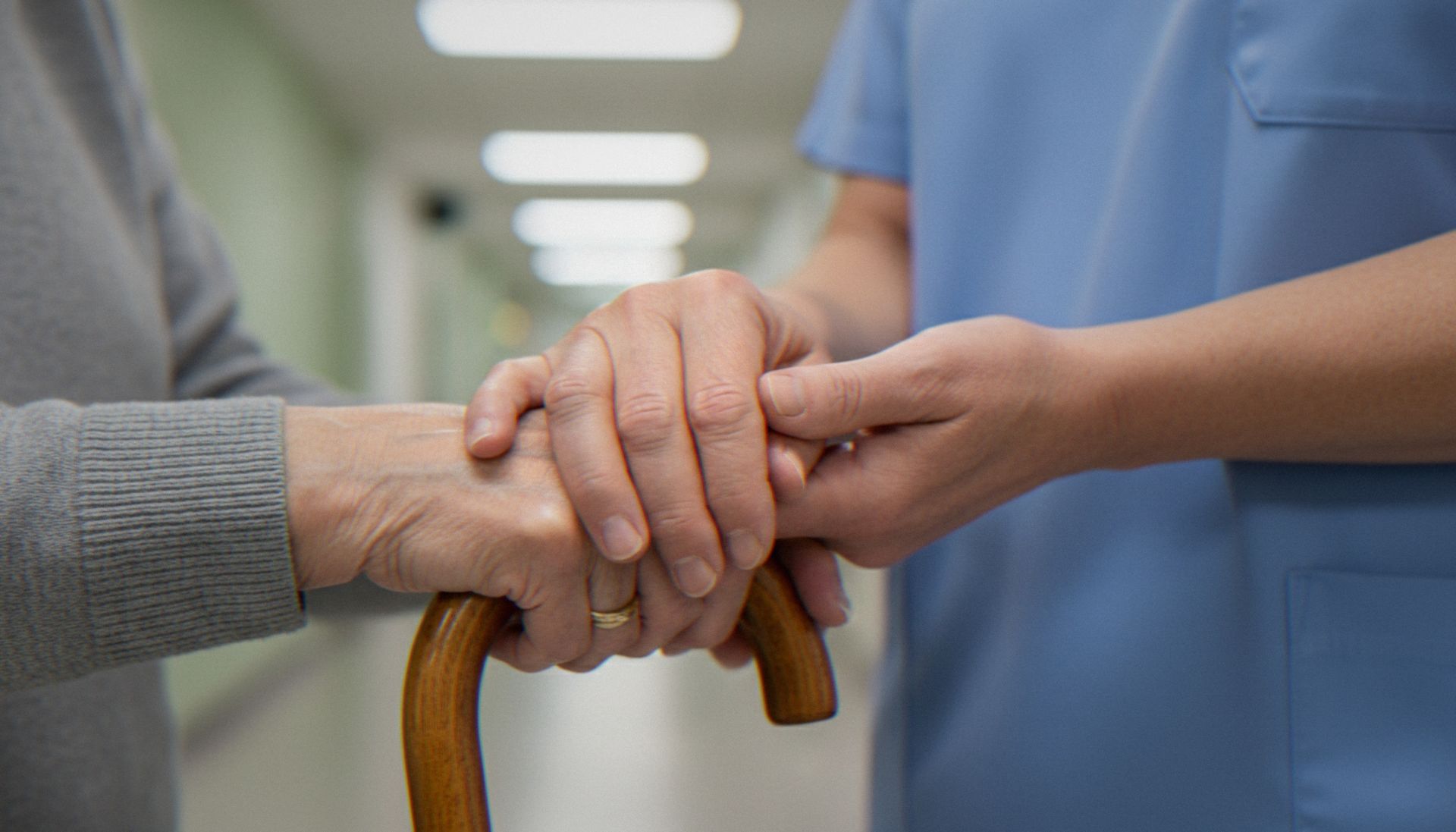 Therapeutenhand stützt die Hand eines Patienten mit Gehstock